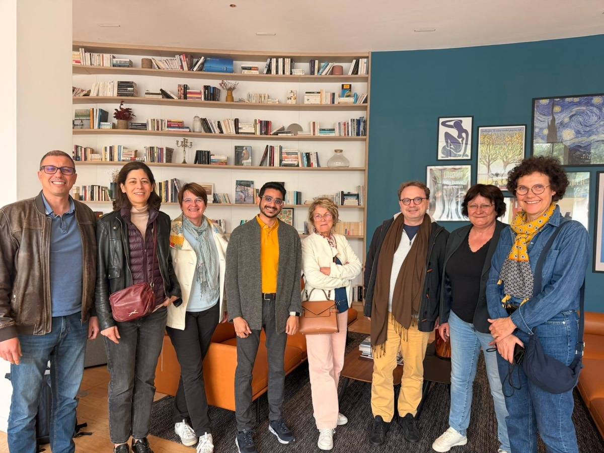 Djouzar entouré d'un groupe de participants devant une bibliothèque